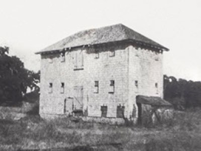a vintage photo of an old building with grass in front of a house