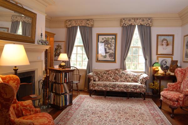Cozy living room with vintage furniture, lamps, and framed pictures.