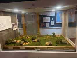 Miniature village diorama in a glass display case with lights.