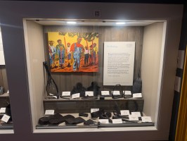 Display case with various shackles, a painting, and an informational plaque.